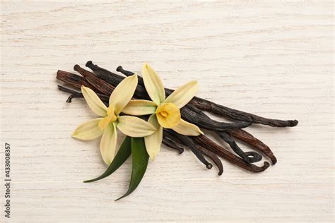 Beautiful vanilla flowers and sticks on white wooden table, flat lay ...