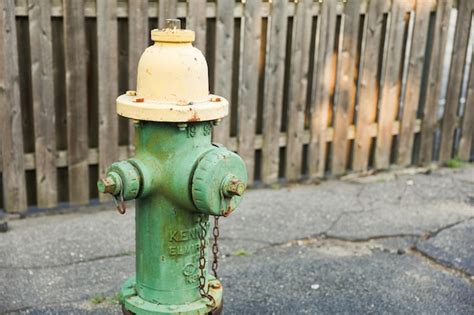 Premium Photo | A green fire hydrant with a yellow top and a chain on it.