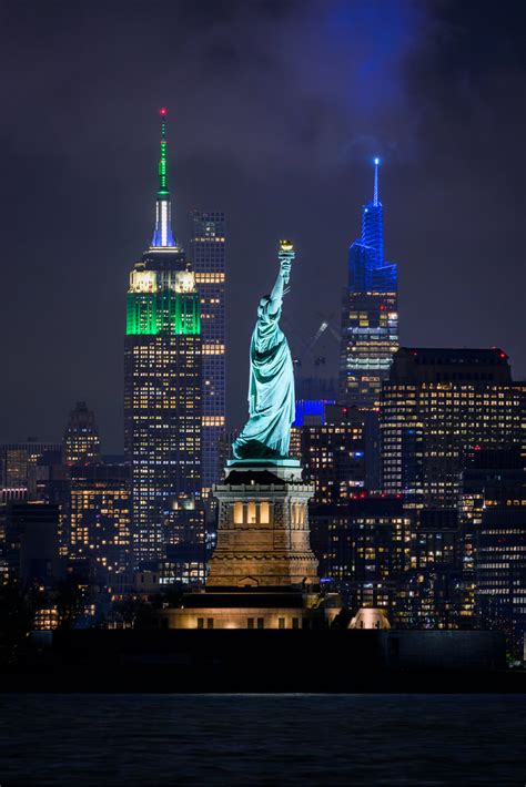 Night view of the Statue of Liberty with the Empire State Building lit ...