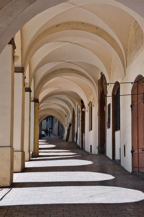 an arched walkway between two buildings with doors and windows on both ...