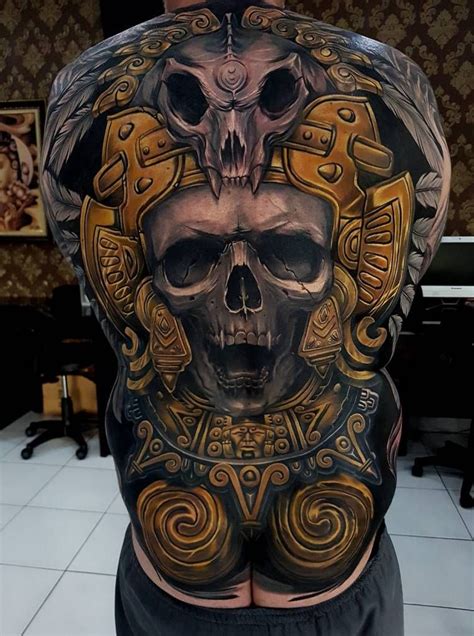 a man's back covered in tattoos with a skull and cross on the chest