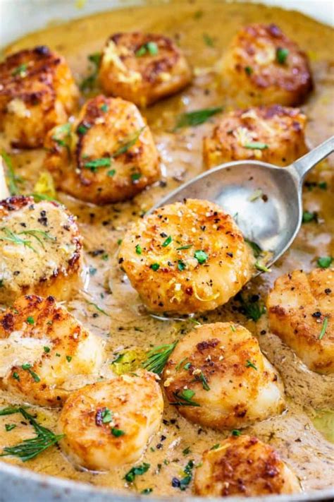 seared scallops with lemon garlic sauce cooking in a pan