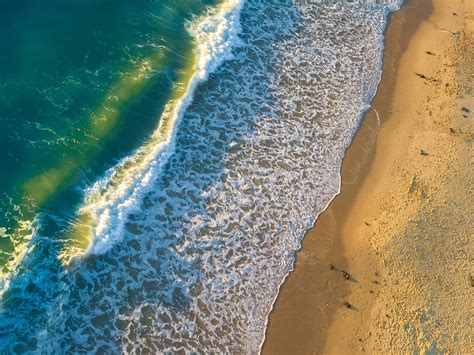 drone view of ocean waves crashing on the sand beach at roker beach ...