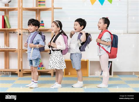 Smiling kindergarten children with backpacks lining up Stock Photo - Alamy