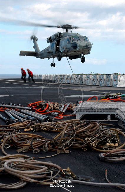 An HH-60H Seahawk helicopter prepares to lift a crate of ordnance ...