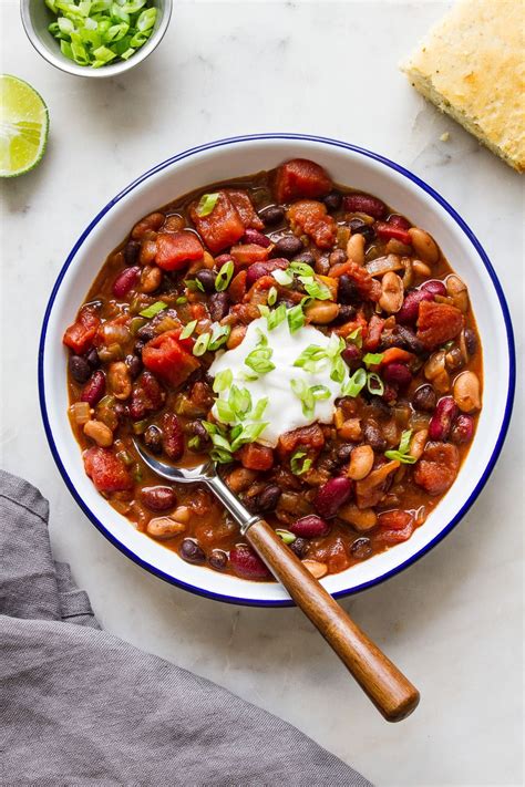 a bowl of chili with beans, sour cream and lettuce on the side