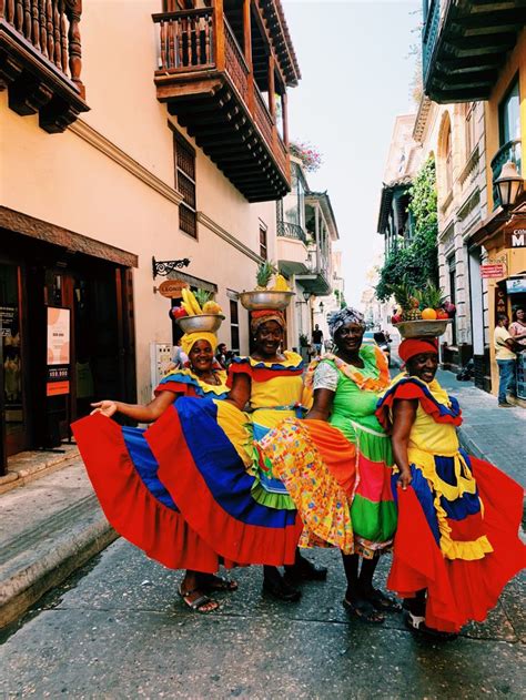 three women in brightly colored dresses are standing on the street with ...