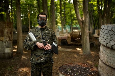 Premium Photo | Warrior in camouflage and mask holds paintball gun ...