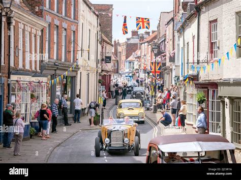 A procession of American and vintage style hot-rod vehicles and ...