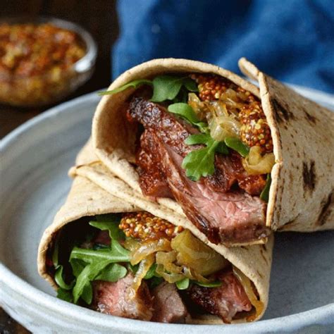 steak wrap with caramelized onions on a white plate next to a blue towel