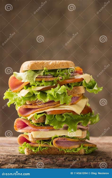 Large Shiny Sandwich with Ham Cheese and Greens on a Wooden Background ...