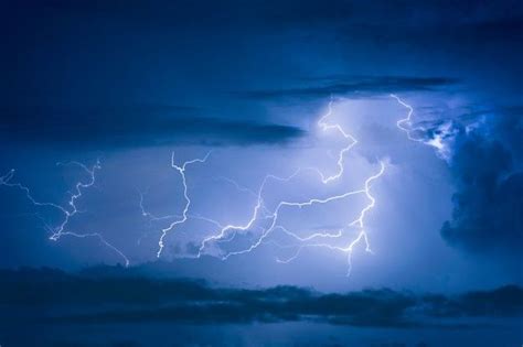 a lightning storm is seen in the sky with clouds and dark blue skies ...