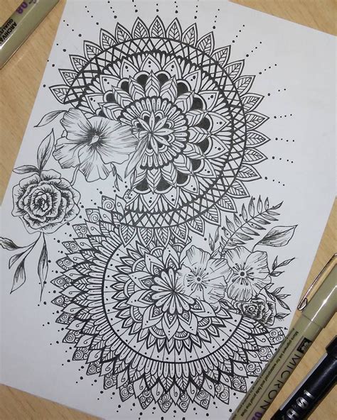 a black and white drawing of flowers on paper next to some crayon pens