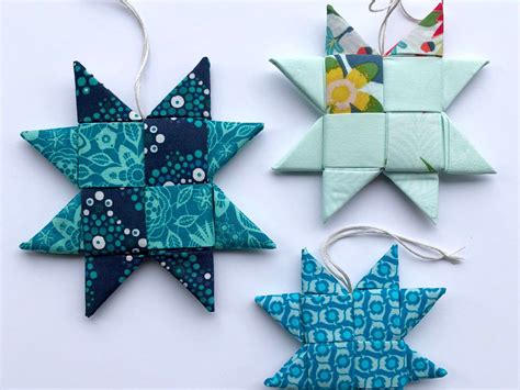 three origami stars hanging from strings on a white surface with blue ...