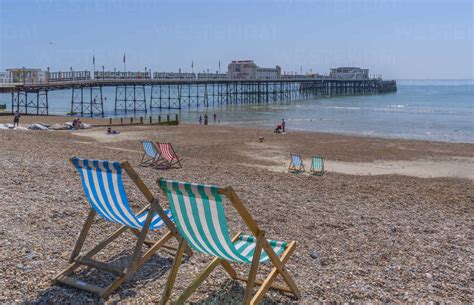 View of Worthing Pier and colourful deckchairs on Worthing Beach ...