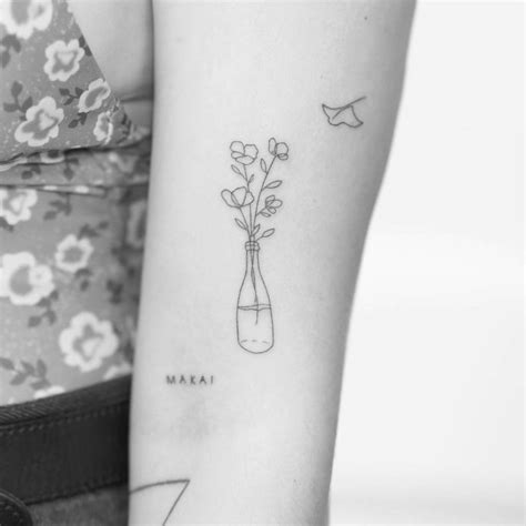 Poppy flowers in a bottle tattooed on bicep