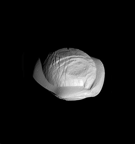 Pan, a small moon of Saturn that orbits within its A-ring. It's gravity ...