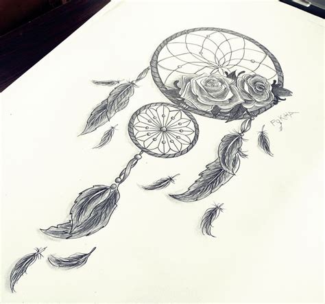 a drawing of a dreamcatch with roses and feathers on the table next to it