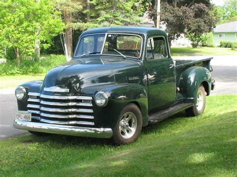 an old green truck parked in the grass