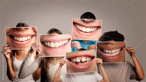 group of happy people holding a picture of a mouth smiling on a gray ...