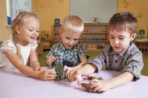 Children playing with animal toys at table in classroom - Stock Photo ...