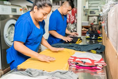 Premium Photo | Employees in uniform folding clothes in a laundry service