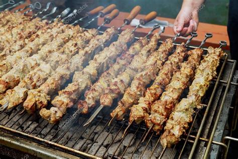 Grilled shish kebab on metal skewer. Chef hands cooking roasted meat ...