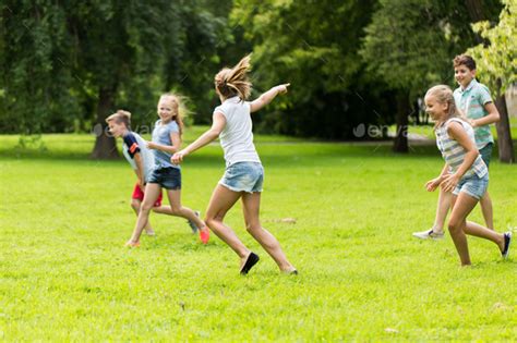 group of happy kids or friends playing outdoors Stock Photo by dolgachov