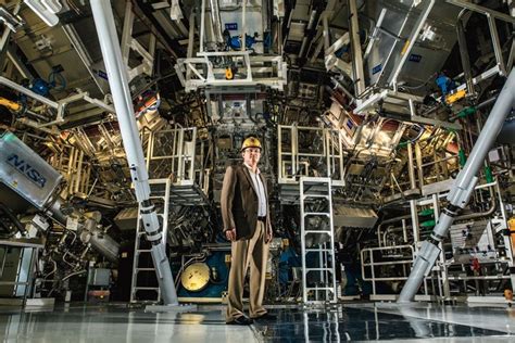 a man in a suit and helmet standing next to an engine on a space station