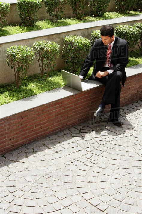 Businessman working on laptop outside - Stock Photo - Dissolve