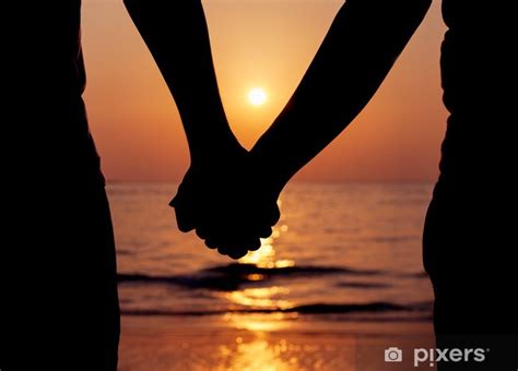 Wall Mural Silhouettes couples holding hands on sunset. - PIXERS.UK