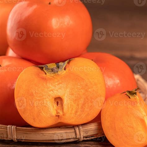 Fresh beautiful sliced sweet persimmon kaki on dark wooden table with ...