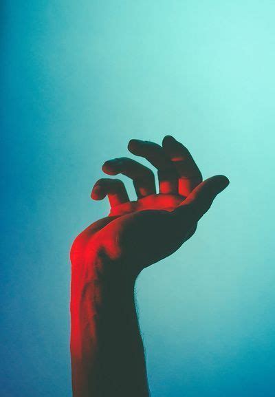 a person's hand reaching up into the air with red light coming from ...