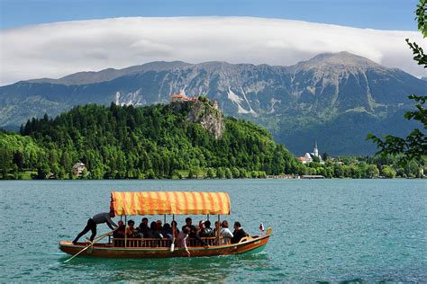 Traditional Pletna boat with colorful canopy on Lake Bled with B ...