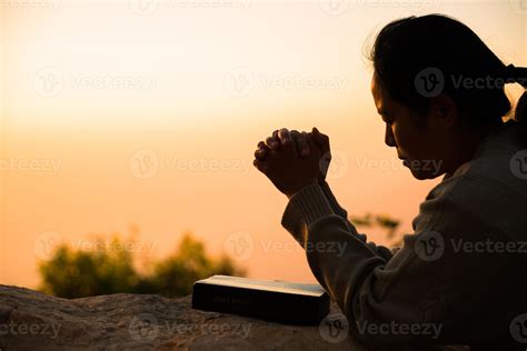 Silhouette of woman kneeling down praying for worship God at sky ...