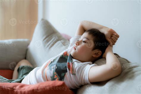 Portrait young boy with curious face sitting on sofa watching cartoon ...