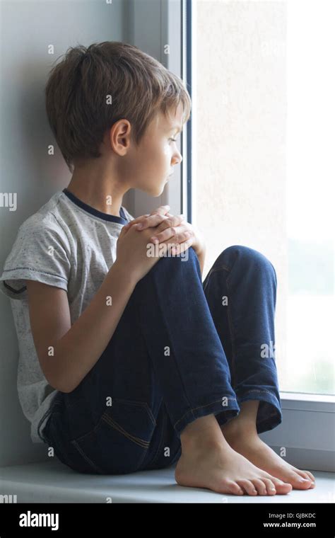 Sad lonely child sitting alone on the window at home Stock Photo - Alamy