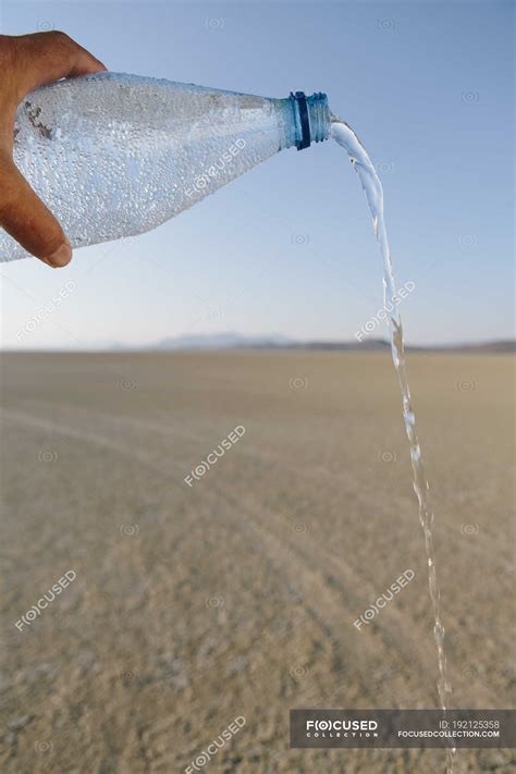 Male hand pouring water from bottle in landscape of Black Rock Desert ...