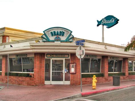 an old brick building with a neon sign on the front and sidewalk next to it