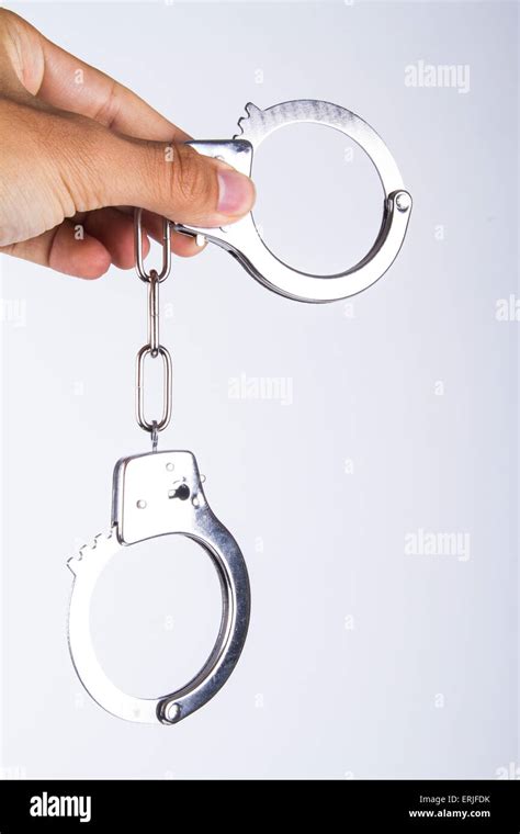 Hand holding handcuffs, isolated on white background Stock Photo - Alamy