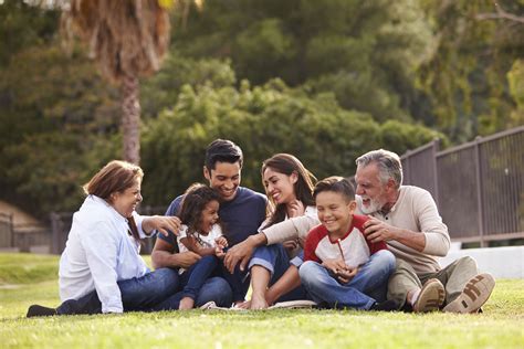 Happy three generation Hispanic family sitting on the grass together in ...