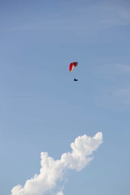 Faceless person flying paraglider over green countryside · Free Stock Photo