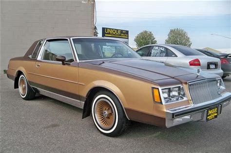 an old car parked in a parking lot next to some other cars and one is brown