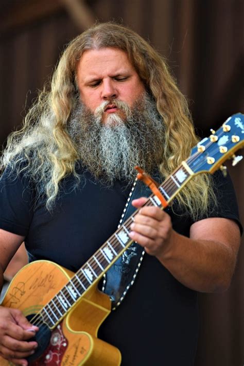 a bearded man with long hair playing an electric guitar