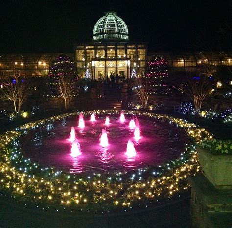 a lighted fountain surrounded by lots of lights in front of a large ...