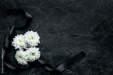 Funeral symbols. White flower near black ribbon on black background top ...