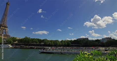 A cruise boat pass next to the Eiffel tower on a sunny day in Paris ...