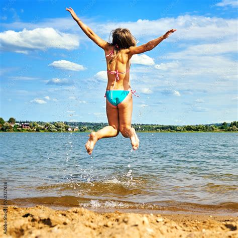 Teenager girl wearing bikini with spreading hands jumps high above the ...