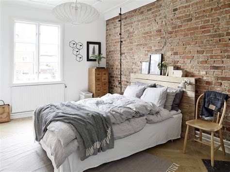 a bedroom with brick wall and white bedding, wooden furniture and rugs ...