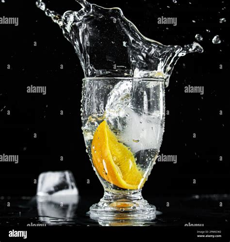 Glass of Water with Orange Slice and Ice Drop Causing Water Splash on a ...